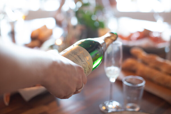 Matfoto med hand som håller i flaska och häller upp champagne